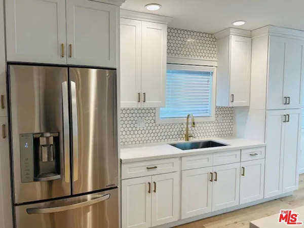 a kitchen with appliances a refrigerator and cabinets
