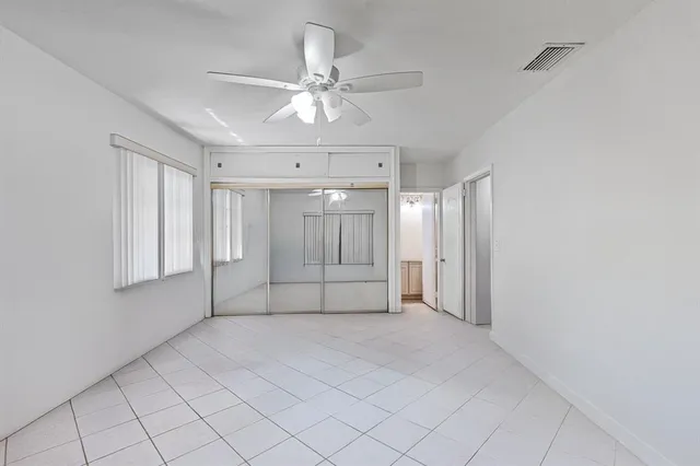 an empty room with windows and fan