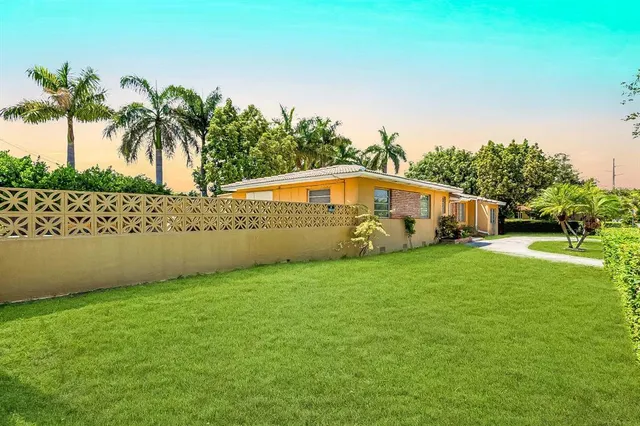 a front view of a house with a yard and palm trees