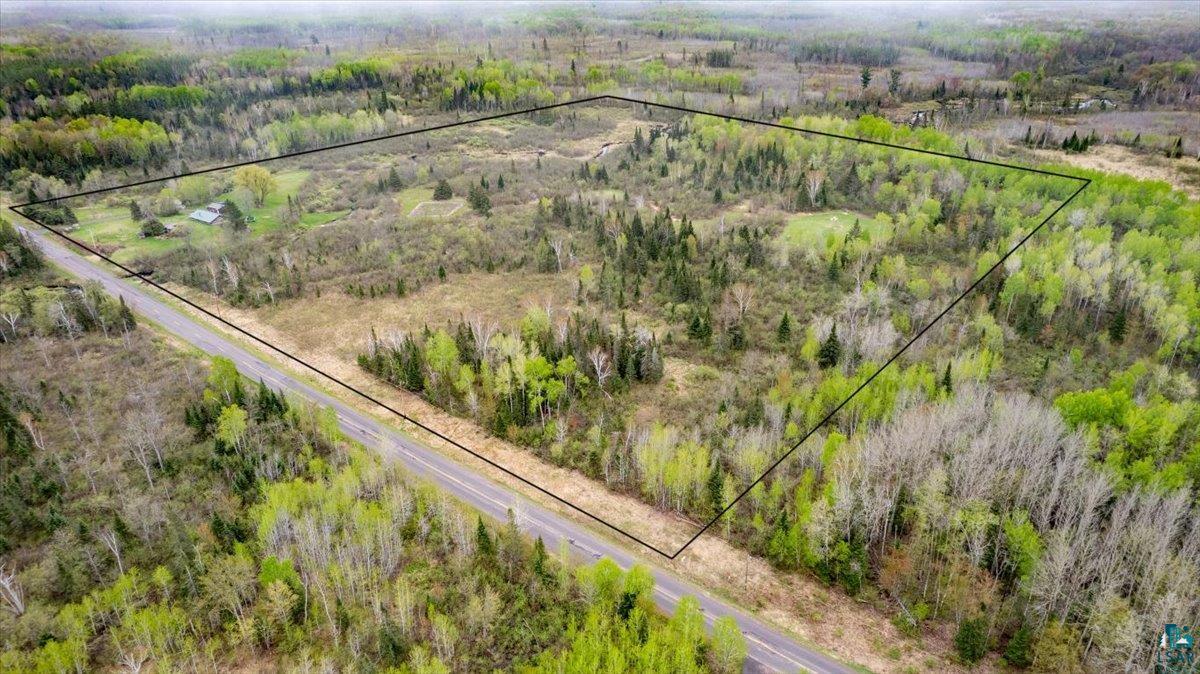 5190 County Road M Gordon, WI 54838 - Photo 7 of 31 Expansive land parcel featuring diverse tree coverage, a prominent roadway bordering one side, and a small structure present within the boundaries