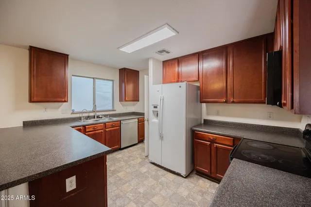 a kitchen with stainless steel appliances granite countertop a refrigerator a sink and a stove