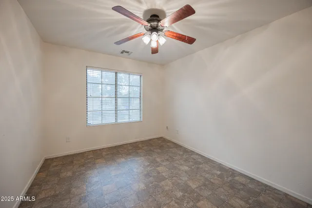 an empty room with windows and chandelier fan
