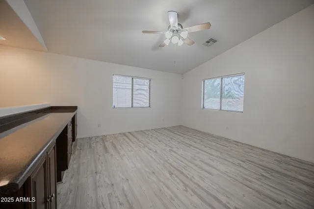 a view of an empty room with a window and wooden floor