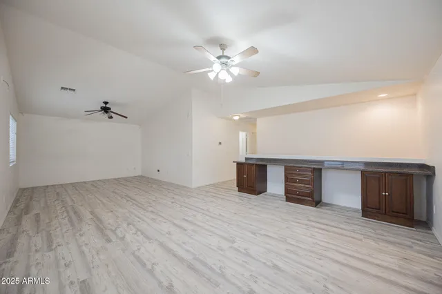 a view of an empty room with a ceiling fan and wooden floor