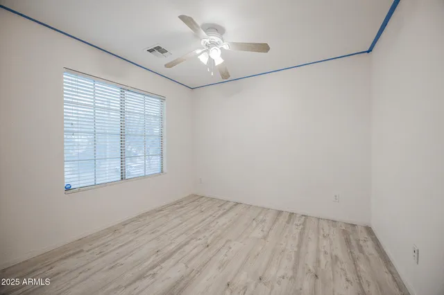 an empty room with a chandelier fan and windows