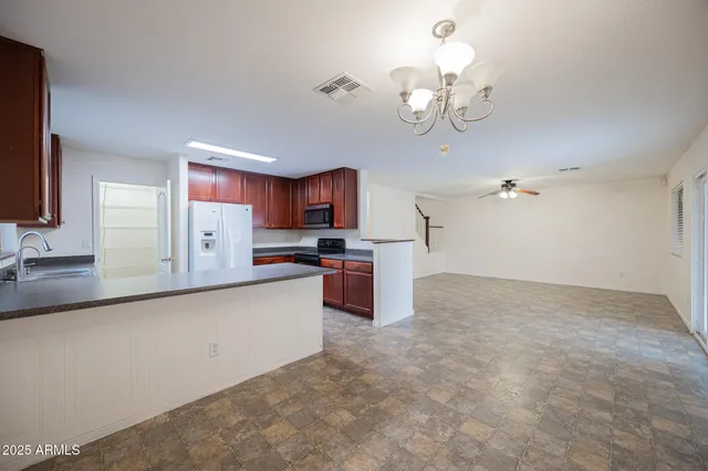 a large kitchen with granite countertop a large counter top space appliances and cabinets