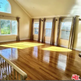 a view of an empty room with window wooden floor and a kitchen area