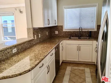 a kitchen with granite countertop white cabinets and white appliances