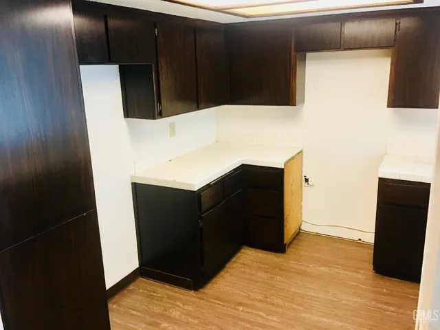 a kitchen with stainless steel appliances a refrigerator a stove a sink dishwasher a dining table and chairs with wooden floor