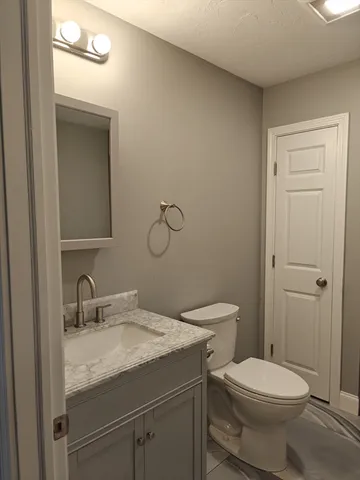 a bathroom with a granite countertop toilet sink and mirror