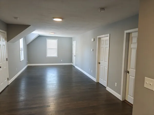 an empty room with wooden floor and windows with curtains