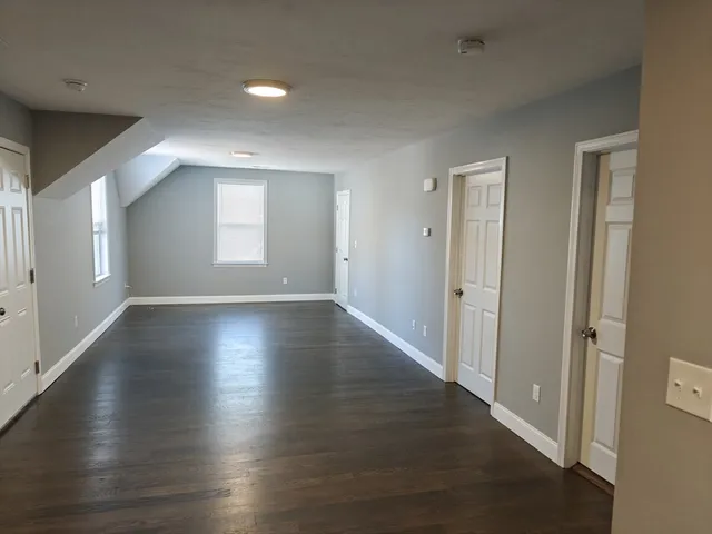 an empty room with wooden floor and windows with curtains