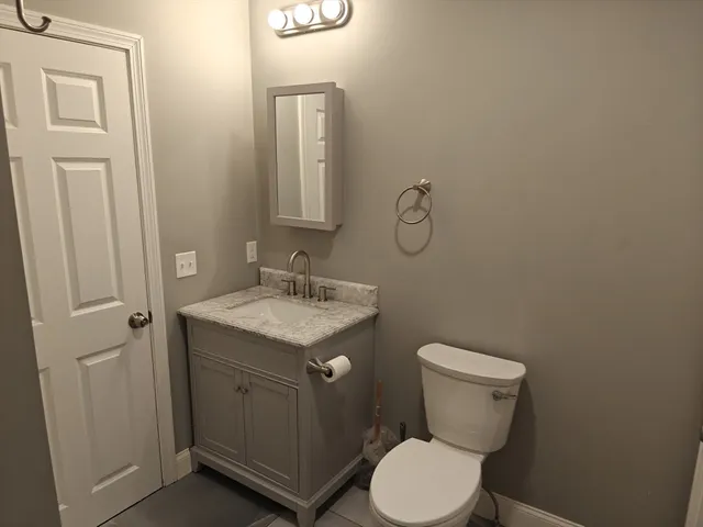 a bathroom with a granite countertop toilet and a sink