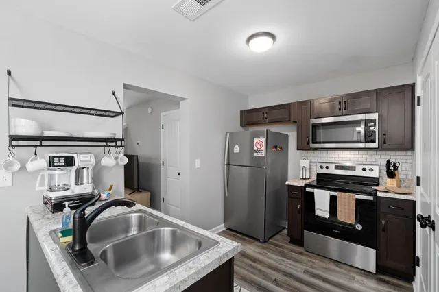 a kitchen with stainless steel appliances granite countertop a sink a stove and a refrigerator