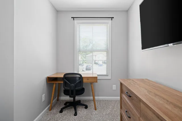 a view of a workspace with furniture and a window