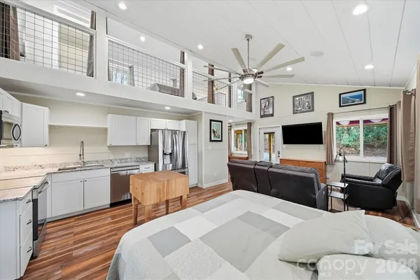 a living room with stainless steel appliances furniture a flat screen tv and kitchen view
