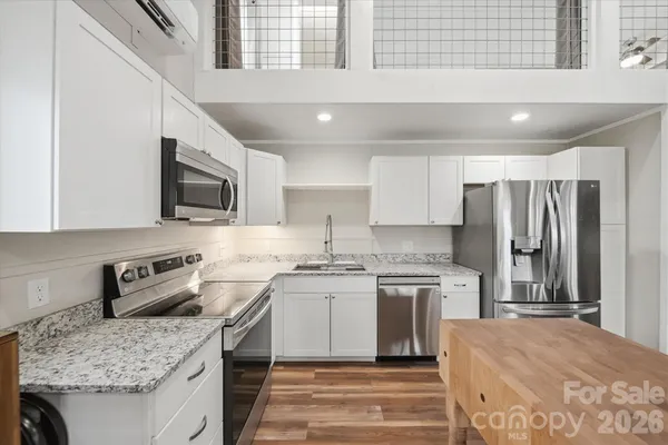 a kitchen with stainless steel appliances granite countertop a sink stove microwave and refrigerator