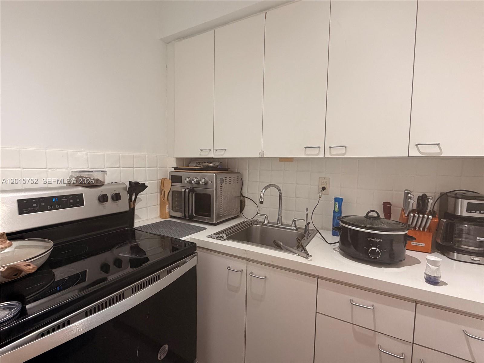 8144 Harding Avenue, Unit 2 Miami Beach, FL 33141 - Photo 10 of 18 a kitchen with a stove and a white cabinets