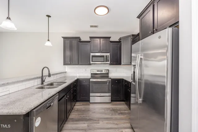 a kitchen with stainless steel appliances granite countertop a sink stove and refrigerator