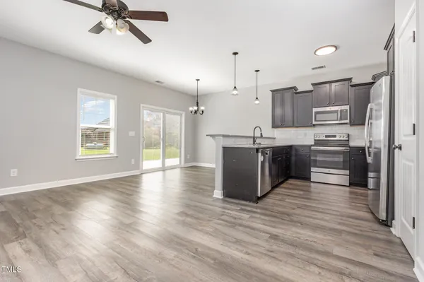 a kitchen with stainless steel appliances granite countertop a stove top oven a sink with wooden floors and cabinets