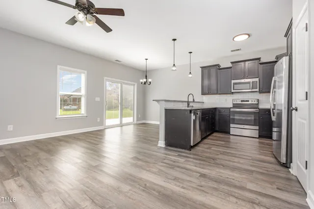 a kitchen with stainless steel appliances granite countertop a stove top oven a sink with wooden floors and cabinets