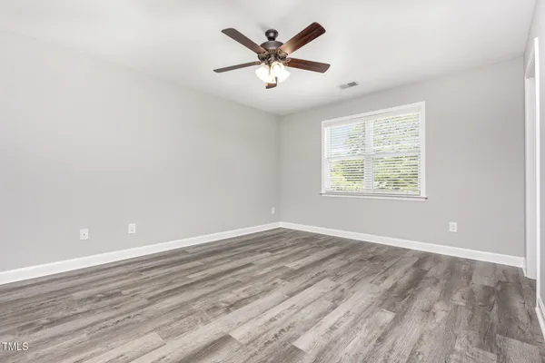 an empty room with wooden floor and ceiling fan
