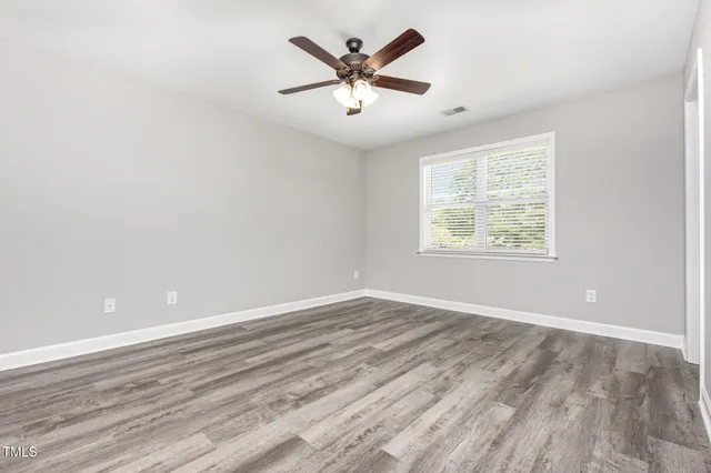 an empty room with wooden floor and ceiling fan