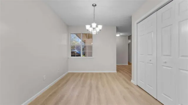 a view of a room with wooden floor chandelier and closet