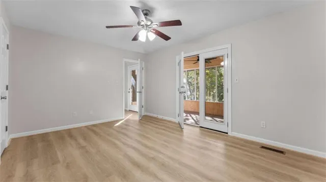 an empty room with wooden floor fan and windows