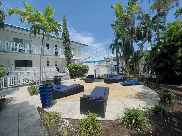 a view of a patio with table and chairs potted plants and large tree