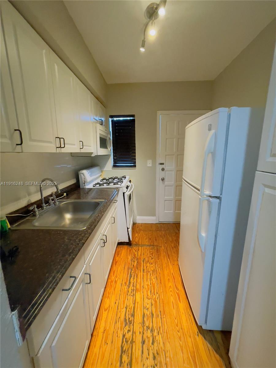 7710 Harding Avenue, Unit 412 Miami Beach, FL 33141 - Photo 4 of 8 a kitchen with a sink appliances and cabinets