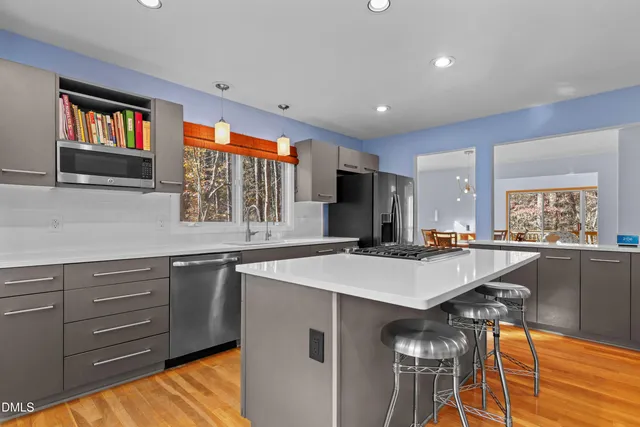 a kitchen with stainless steel appliances a table and chairs in it