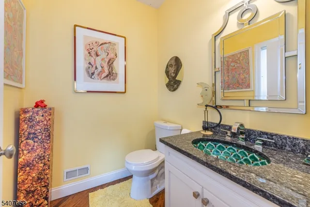 a bathroom with a granite countertop sink mirror vanity and toilet