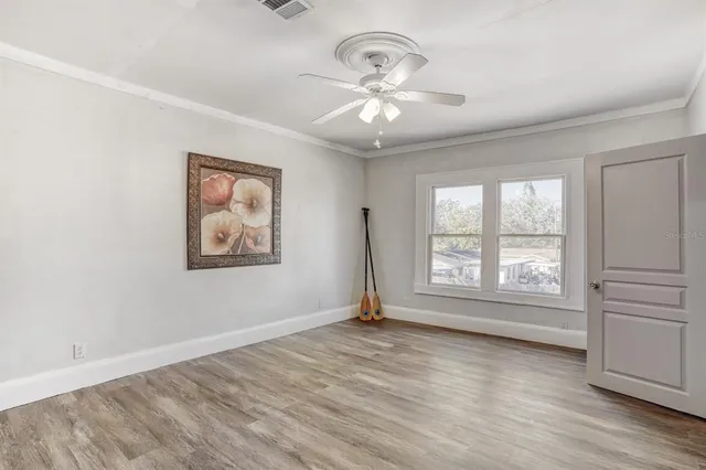 an empty room with wooden floor fan and windows