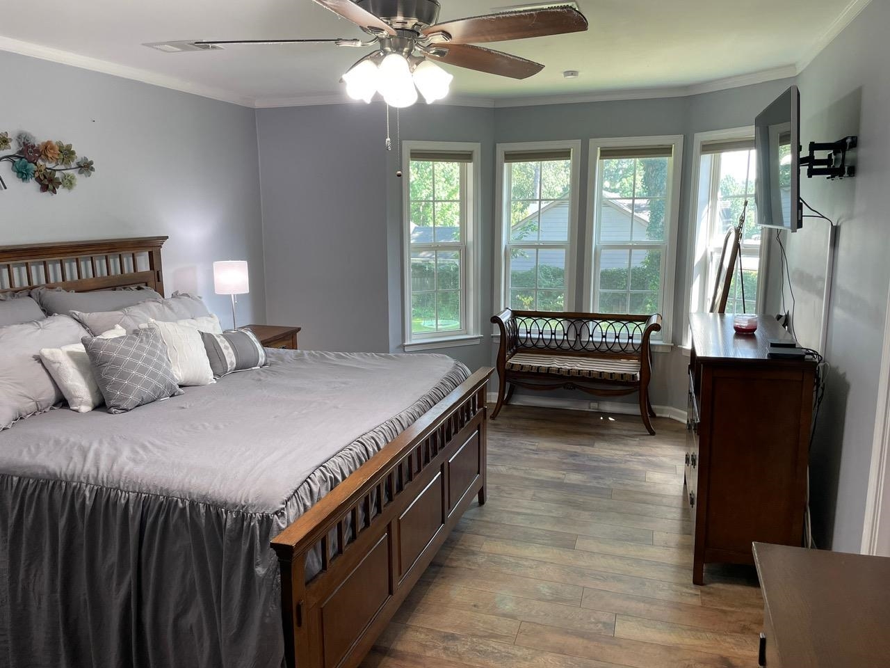 Bedroom with hardwood / wood-style flooring, crown molding, and a ceiling fan