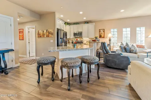 a living room with couches chairs and kitchen view with wooden floor