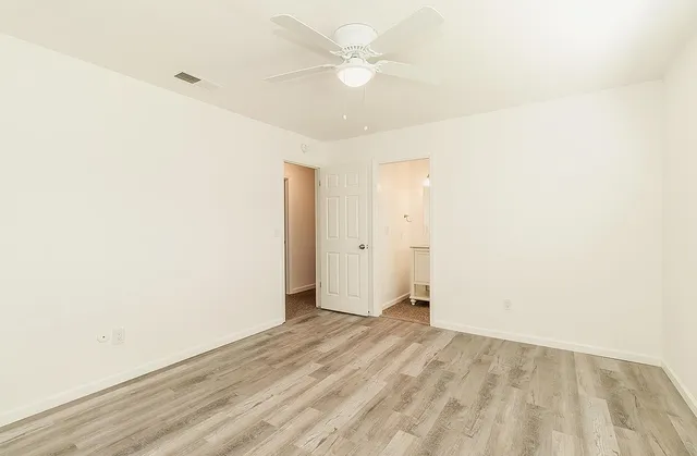 an empty room with a ceiling fan and a window