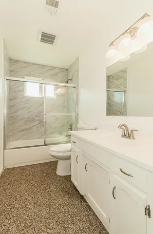 a bathroom with a granite countertop sink a toilet and shower