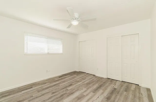 an empty room with a ceiling fan and window