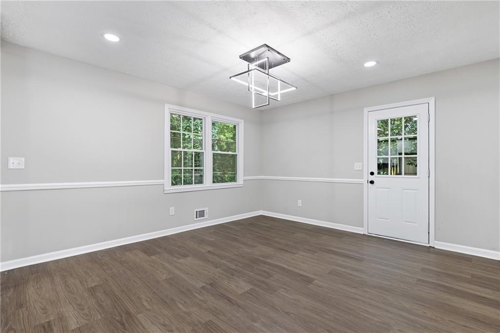 353 Old Rosser Road Stone Mountain, GA 30087 - Photo 14 of 46 an empty room with wooden floor chandelier and windows