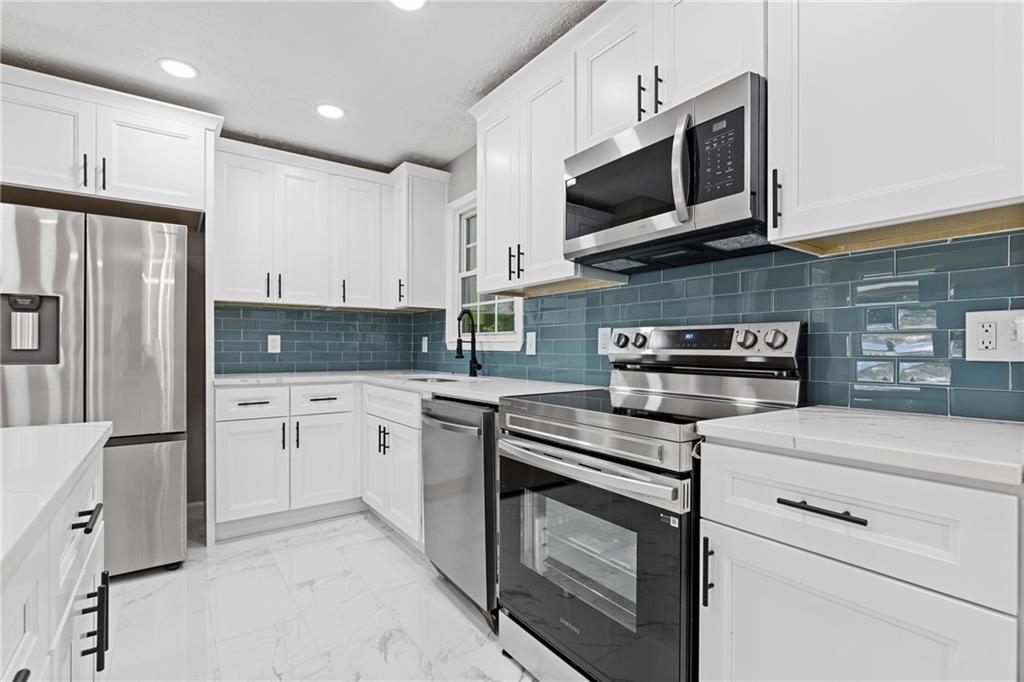 353 Old Rosser Road Stone Mountain, GA 30087 - Photo 10 of 46 a kitchen with stainless steel appliances granite countertop a stove microwave and refrigerator