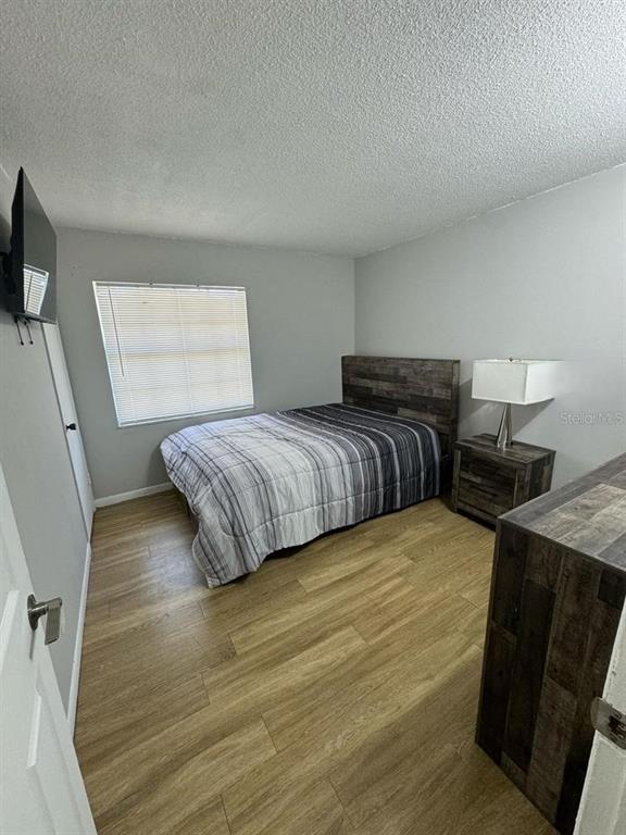 1649 West Oak Ridge Road, Unit 1649C Orlando, FL 32809 - Photo 8 of 8 a bedroom with a bed and wooden floor