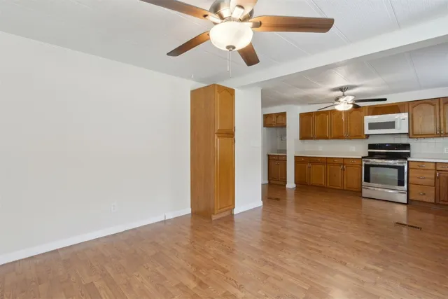 a view of kitchen with stainless steel appliances wooden floor and window