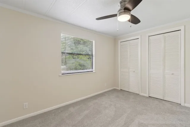 an empty room with windows and fan