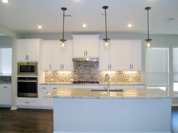 a kitchen with kitchen island granite countertop a sink a counter top space appliances and cabinets
