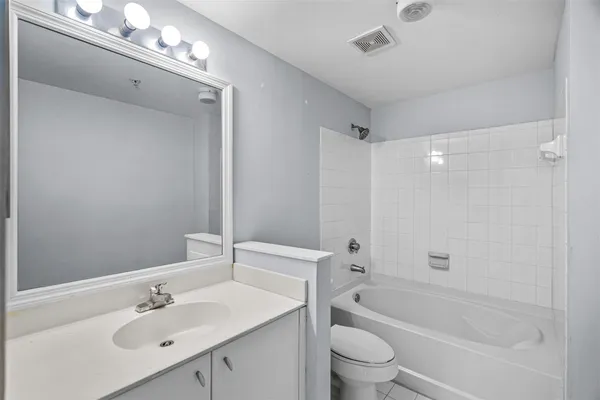 a bathroom with a bathtub shower sink vanity mirror and toilet