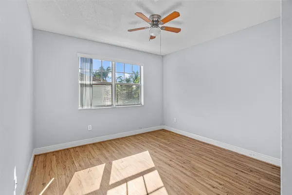 a view of room with hardwood floor and a ceiling fan