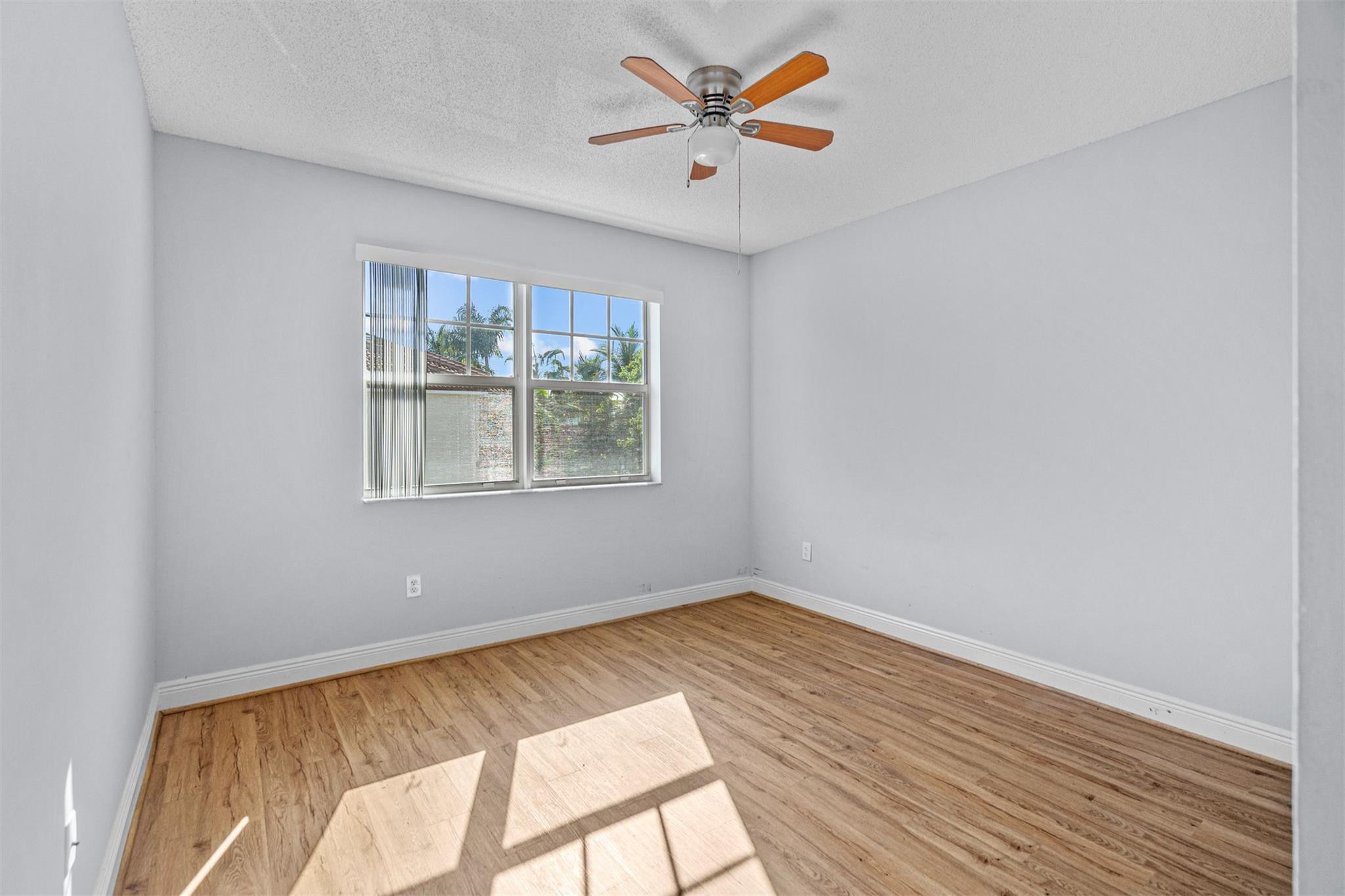 5880 West Sample Road, Unit 307 Coral Springs, FL 33067 - Photo 19 of 25 a view of room with hardwood floor and a ceiling fan