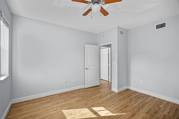 a view of empty room with wooden floor and fan