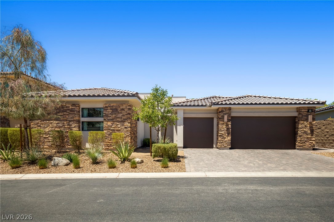 45 Garibaldi Way Henderson, NV 89011 - Photo 2 of 74 A well-kept front facade showcasing attractive stone accents and a paver driveway.